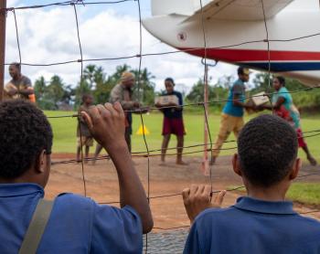 Boys watch as a plane is unloaded at a remote airstrip