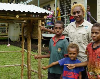 Yanu Kagayo standing with three local kids in front of the cleaning kit