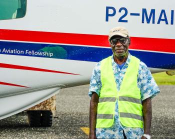 A man stands in front of a small plane