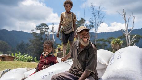 Dusin Villagers sit atop mounds of coffee waiting to be loaded on MAF plane.