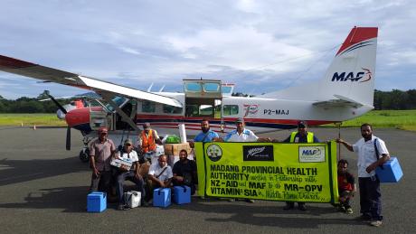 a team from the Madang Provincial Health Authority posing with a banner to say thank you to MAF and NewZealand Aid for their support for the Measles-Rubella Supplementary Immunization Activity (MRSIA) campaign