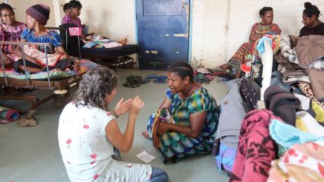 Michelle talking to a mother in hospital while others watch from their beds