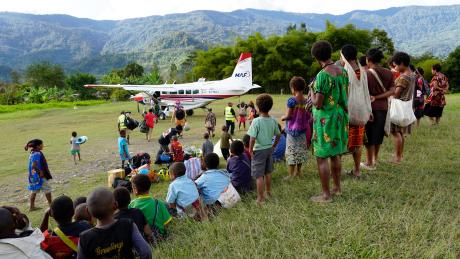people at a remote airstrip waiting to board the aircraft and send people off