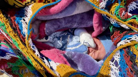 a newborn baby snuggled up in a bilum