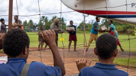 Boys watch as a plane is unloaded at a remote airstrip