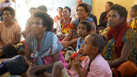 A group of women and girls listen to training