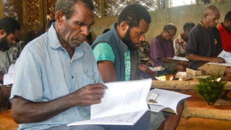 A man sits and reads the Bible and a workbook