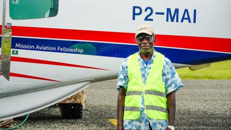 A man stands in front of a small plane