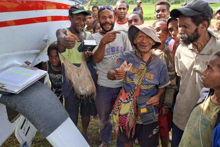 MAF PNG Caravan P2-MAL at Munbil, where people are buying resources from the Bible Box and showing their thumbs up as an acknowledgment that this ministry is available again.