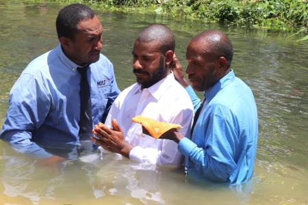 MAF Technologies representative, Nicholas Jowapo assisting in baptising a new believer in the water.