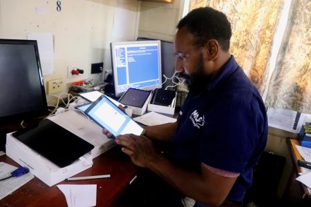 .MAF Technologies IT officer, Ishmael Doroware, Installing translation software into the Wycliffe Tablets prior to distribution.