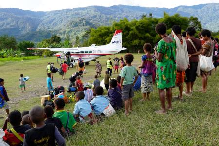 people at a remote airstrip waiting to board the aircraft and send people off