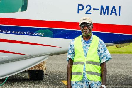 A man stands in front of a small plane