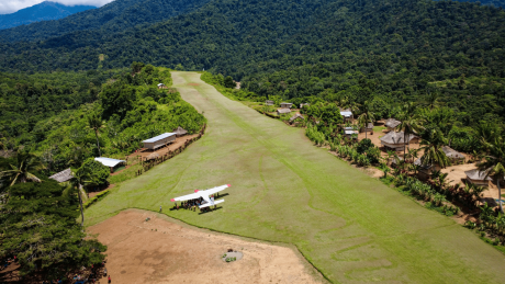 Aerial view of a MAF plane at Yambaitok airstrip with locals gathered around