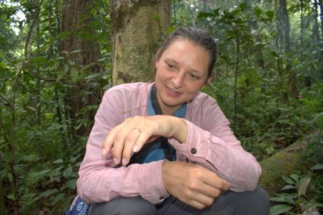Elisabeth Hein examining an insect sitting on her hand while in the forest