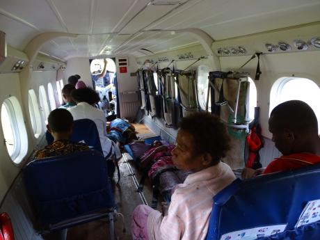 inside the cabin of the Twin Otter with 2 women laying on stretchers and all other seats taken