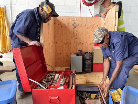 two work men unpacking a tool box containing lots of small sockets and screw drivers 