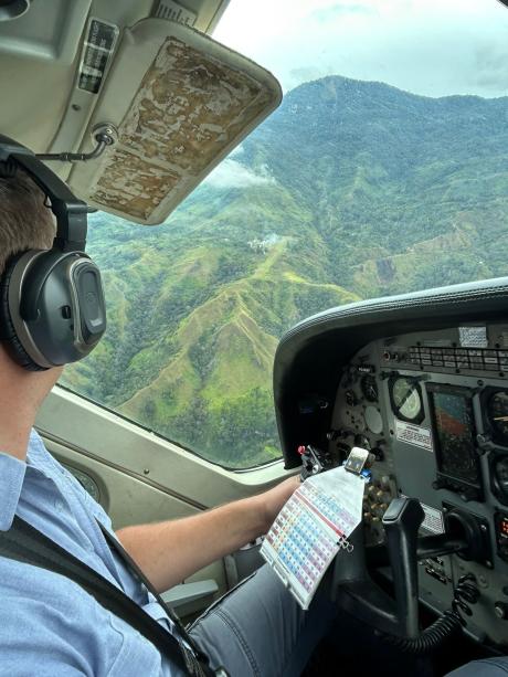 looking out the window of the Cessna Caravan over the shoulder of the pilot following his view to the airstrip of Sindeni
