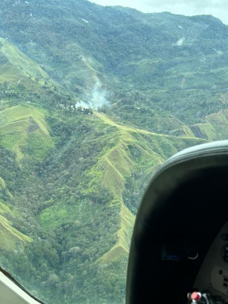 looking out the window of the Cessna Caravan with the airstrip of Sindeni showing smoke rising up at its top