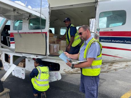loading the boxes into our MAF Caravan, with pilot Brad Venter checking the paperwork and two traffic officers loading