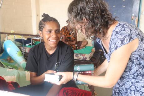 Michelle giving a Bible to one of the young mothers who receives it with a big smile