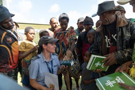 Pilot Bridget Ingham kneeling next to the plane surrounded by a group of people of which some purchase Bibles