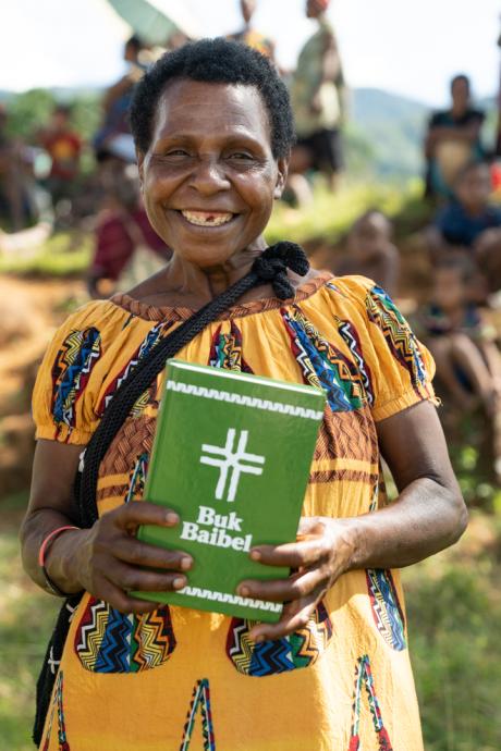 a proud owner of a new Buk Bible - a woman smiling as she poses for a photo with her newly purchased Bible