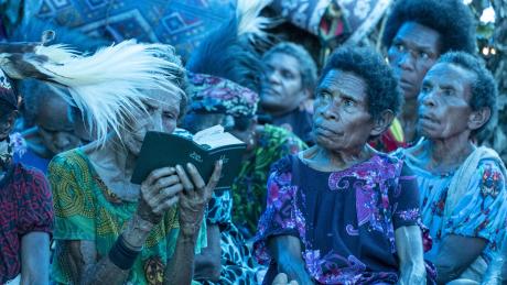 Women in the audience focussed listening to the speaker with one woman reading her Bible