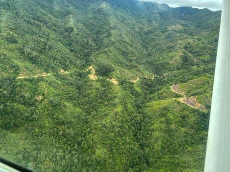 arial shot of remote PNG - a dirt road cutting through the jungle