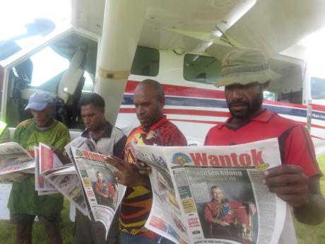 Group of Hesalibi locals reading newspaper delivered by Bridget Ingham.