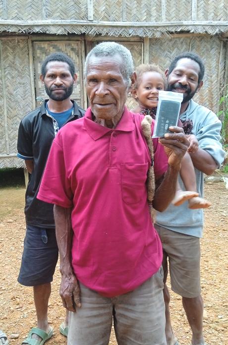 An elderly man holding a Audio Bible device while posing for a picture at his remote village of Simbai, Madang province of PNG