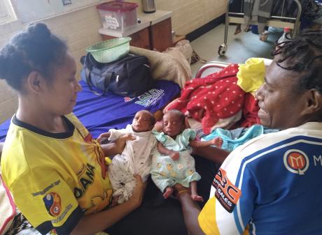 Two mothers holding young babies in the hospital.