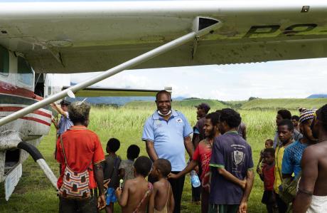 Richard Jacob, SDA Mission Western Highland Area Supervisor, standing by MAF plane being greeted by Mamusi locals.