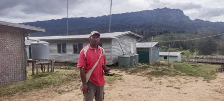 A man stands near school buildings in remote PNG