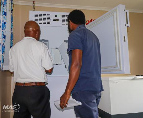 MAF Technologies Technician Steven Zato assisting a health worker with basic guidelines on using a solar-powered vaccine fridge