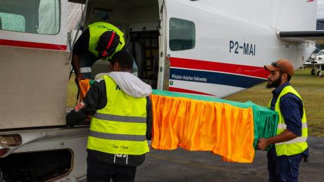 Casket being lifted unto MAF plane by traffic officer