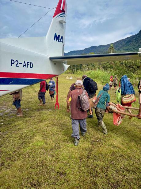 Locals carrying the sick boy to the MAF plane.