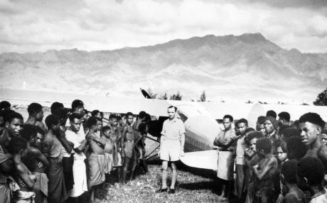 A white pilot and local people surround a small plane in the New Guinea highlands