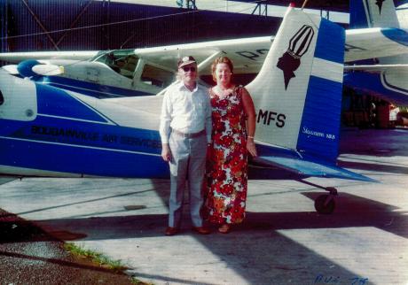 A man and woman stand in front of a small plane