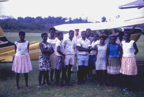 A group of young people next to a small plane