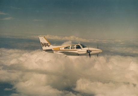 A twin engine aeroplane flies above the clouds