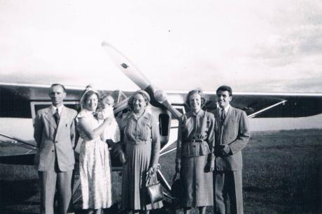 A group of people pose in front of a small plane