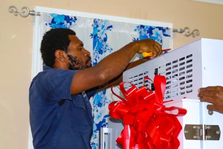 MAF Technologies technician Noah Siso installs a solar-powered vaccine refrigerator at Chuave Rural Hospital.