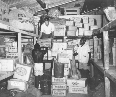 Three men gather cargo boxes in a freight room